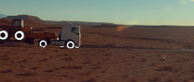 a truck driving down a dirt road in the middle of the desert