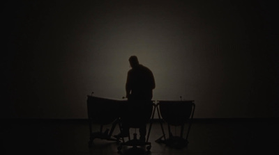 a man standing in the dark with two chairs