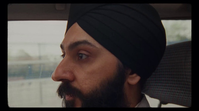 a man in a turban looks out the window of a car