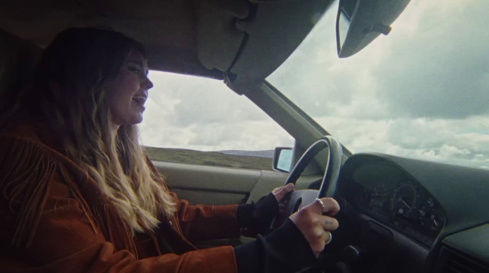 a woman driving a car on a cloudy day