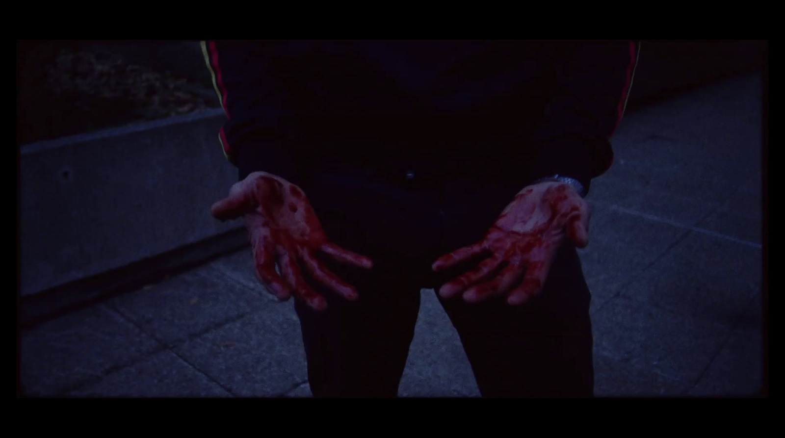 a person with blood on their hands standing on a sidewalk