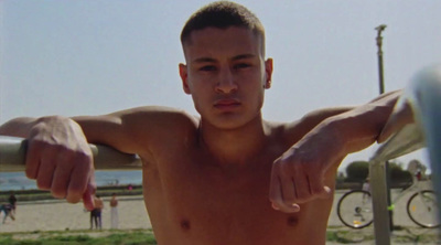 a shirtless man holding a skateboard on a beach