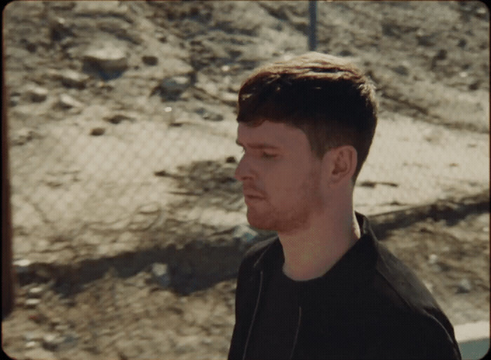 a man standing in front of a fence with his eyes closed