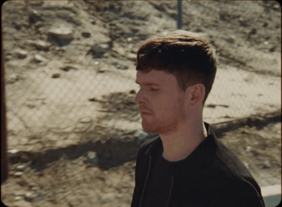 a man standing in front of a fence with his eyes closed