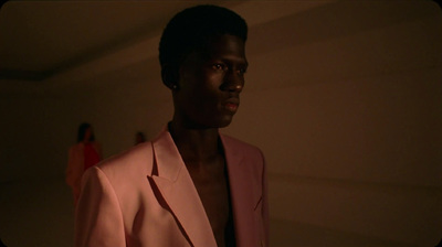 a man in a pink suit standing in a room