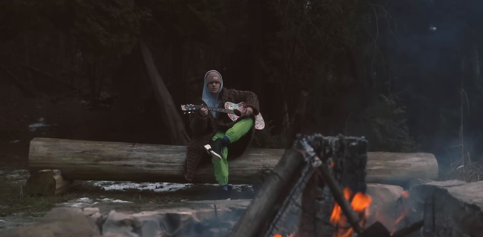 a man sitting on a log playing a guitar