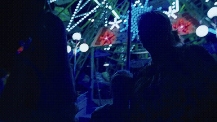 a person standing in front of a ferris wheel at night