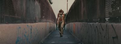 a woman walking down a street next to a wall