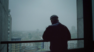 a man standing in front of a window looking out at a city