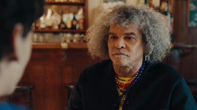 a man with an afro talking to a woman in a bar