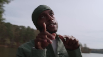 a man in a green jacket pointing at something