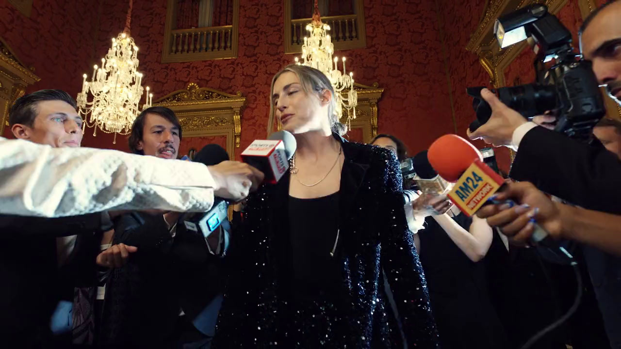 a woman in a black dress is surrounded by reporters