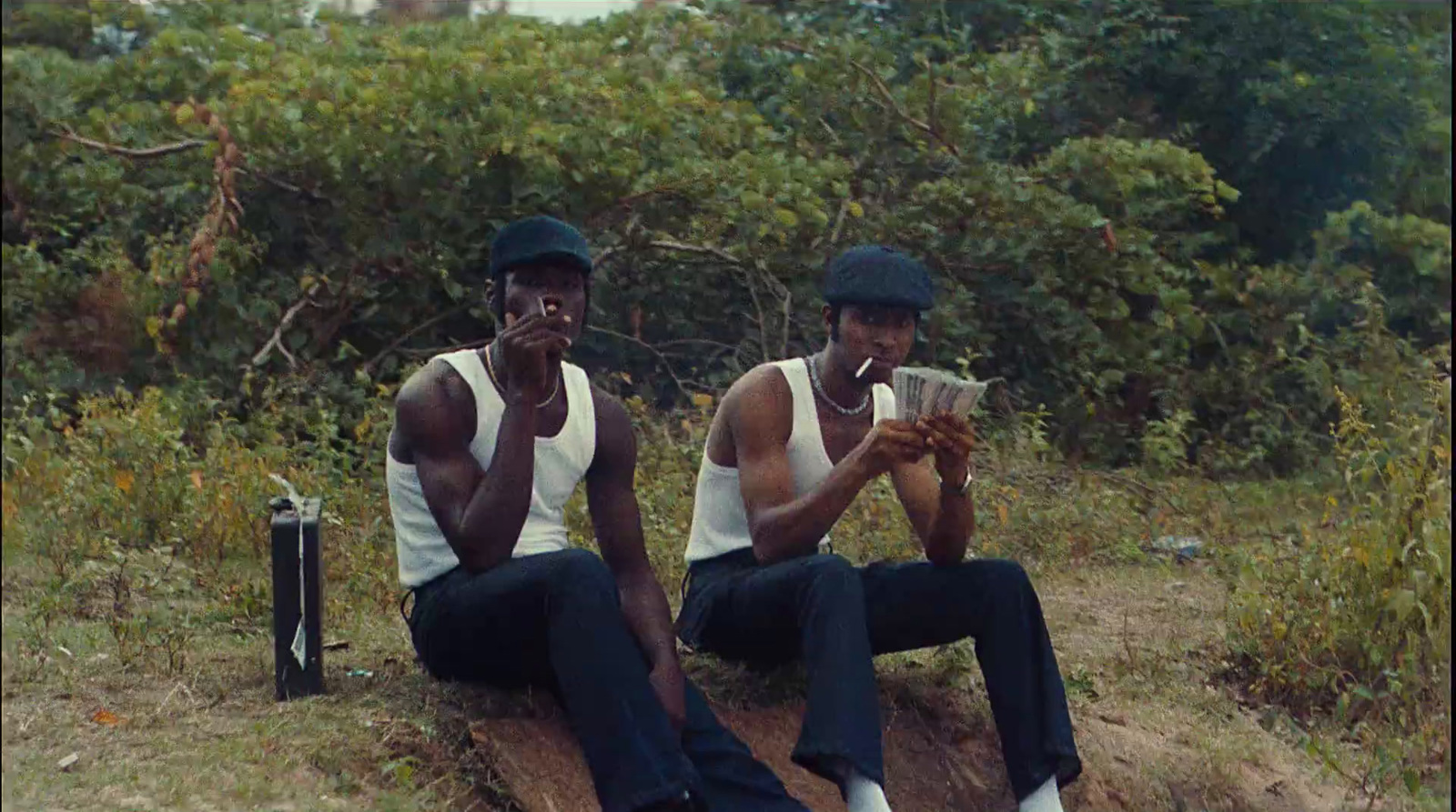 two men sitting on a log in the woods