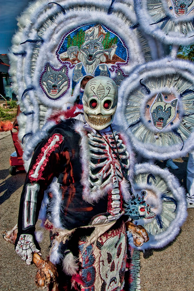 a skeleton in a costume standing in front of a sign