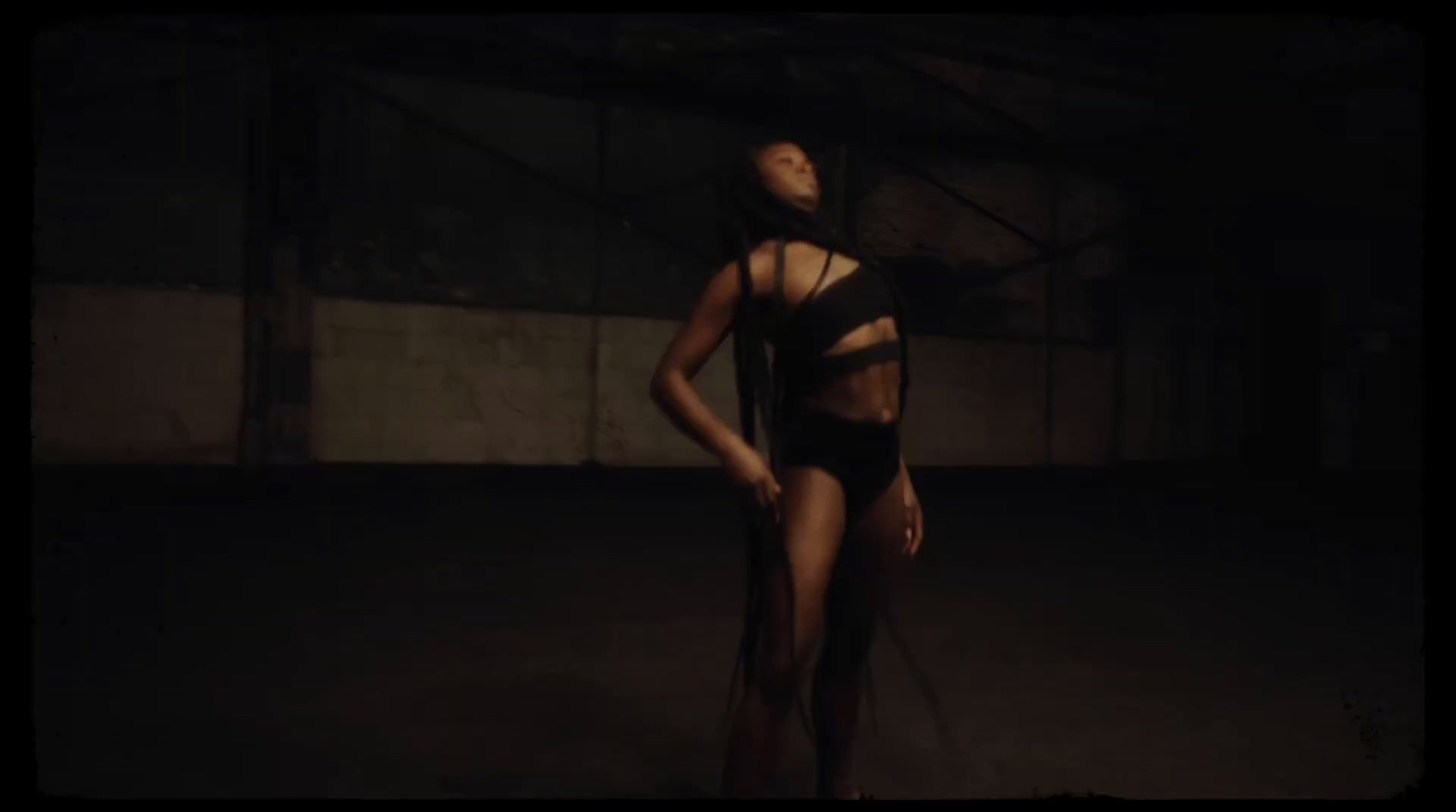 a woman in a black bodysuit standing in a dark room