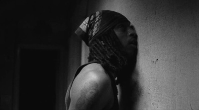 a man with dreadlocks standing next to a wall