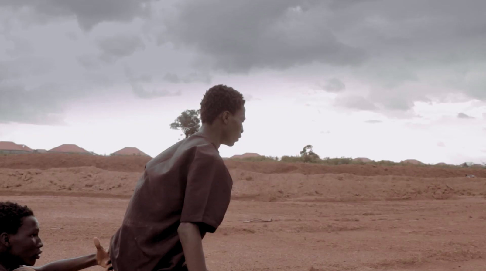 a couple of men standing next to each other on a dirt field