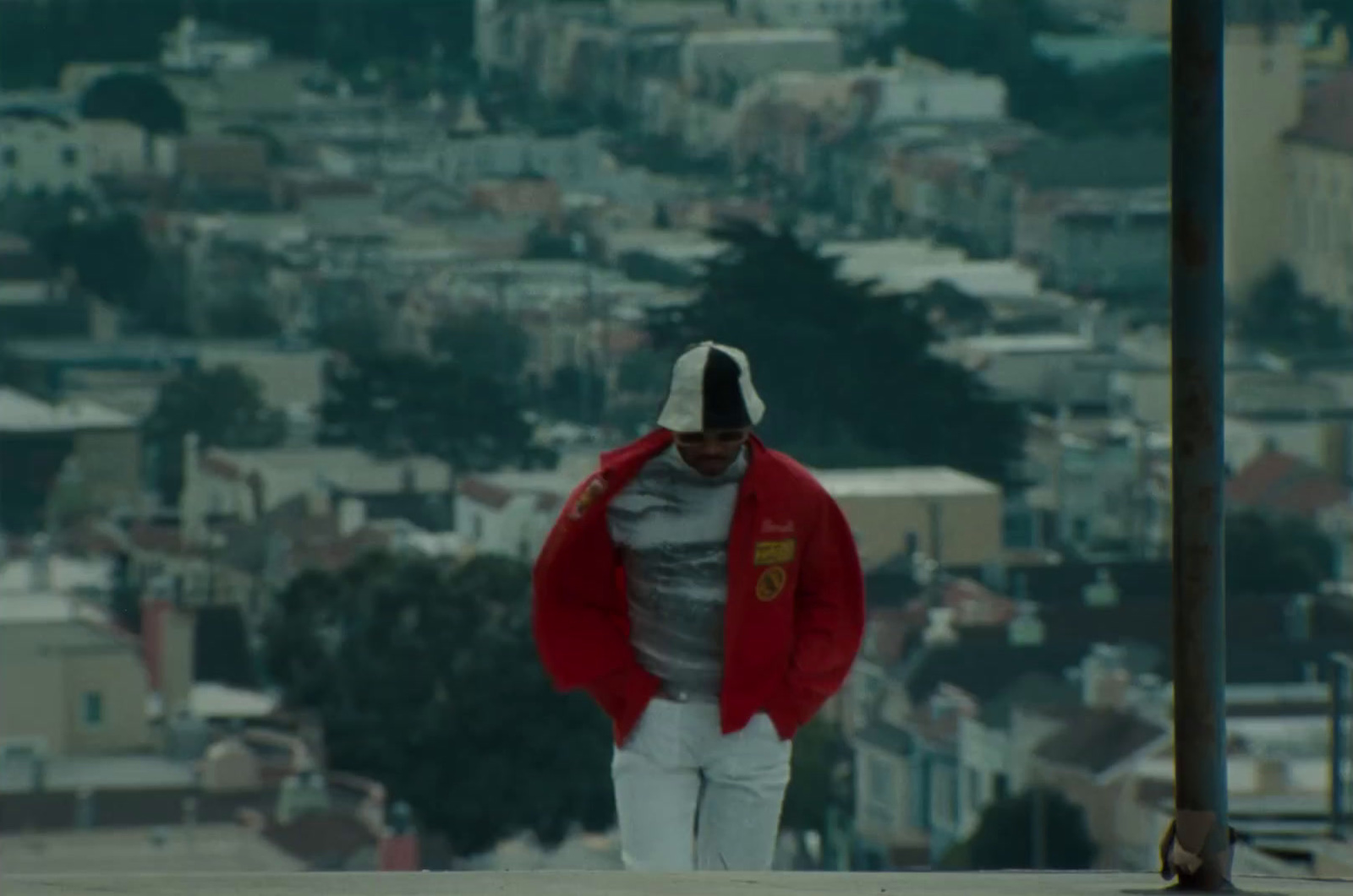 a man in a red jacket walking down a hill