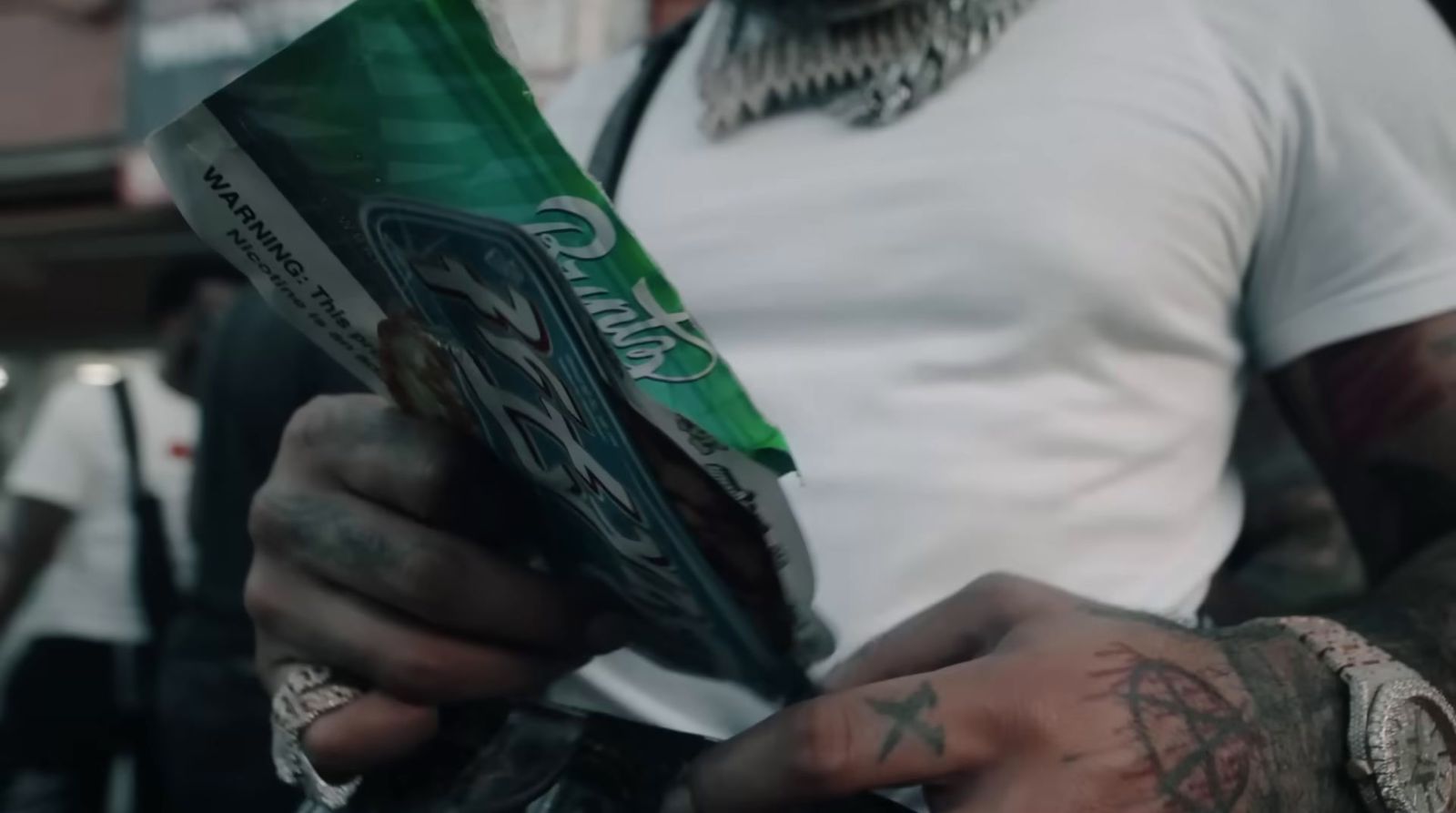 a tattooed man holding a pack of candy