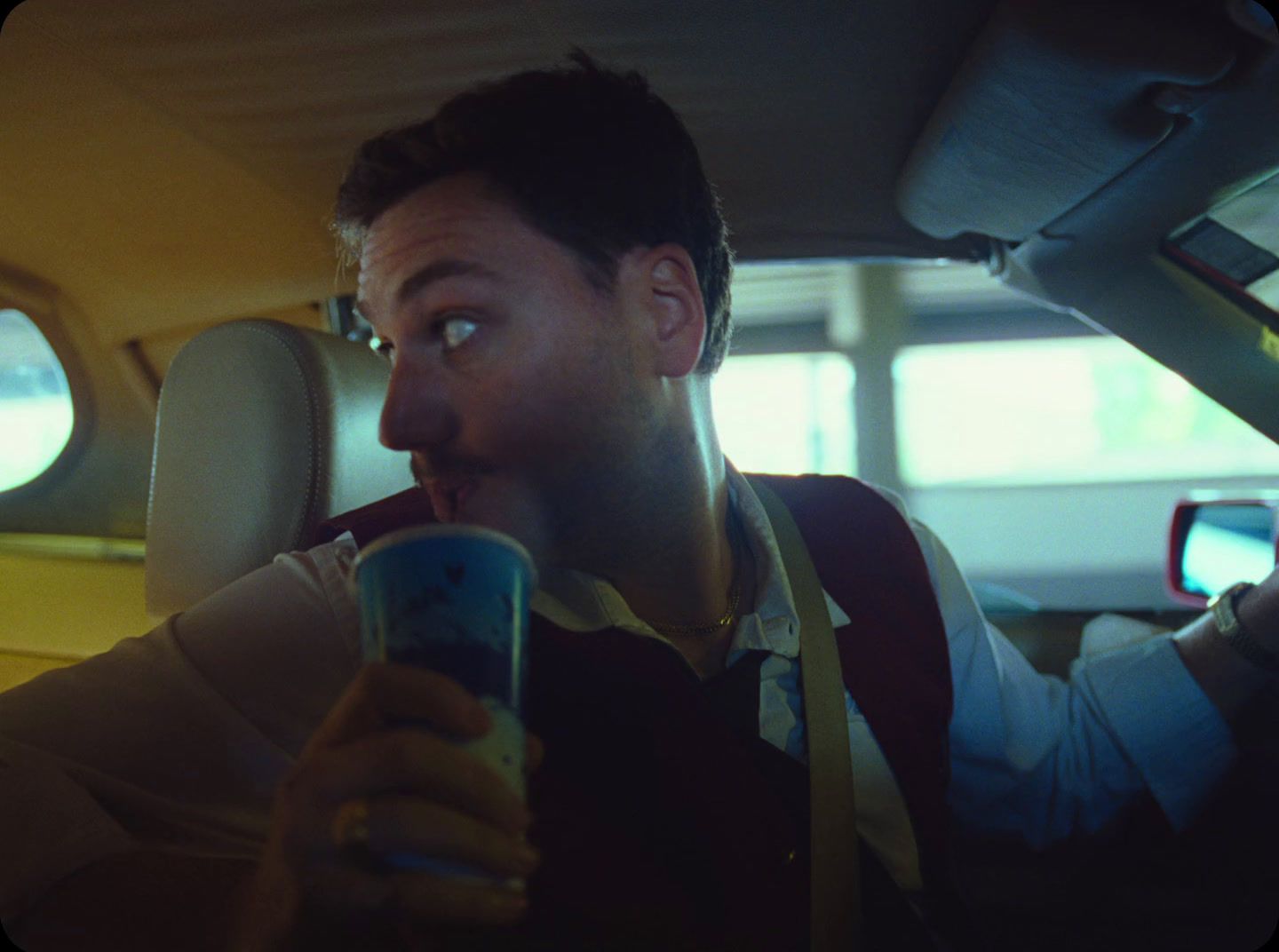 a man sitting in a car holding a cup