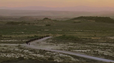 a group of people walking down a dirt road