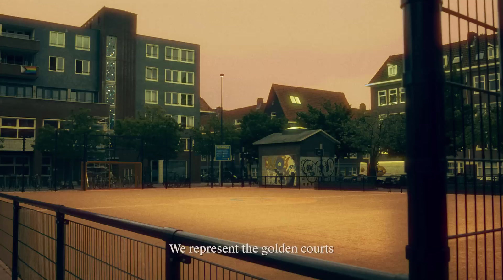 a tennis court surrounded by buildings and a fence