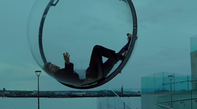 a man laying in a glass ball hanging from the side of a building