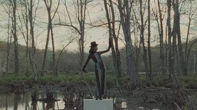 a statue of a woman standing in the middle of a swamp