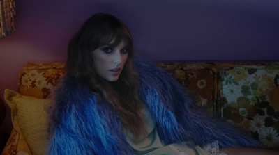 a woman sitting on a couch wearing a fur coat