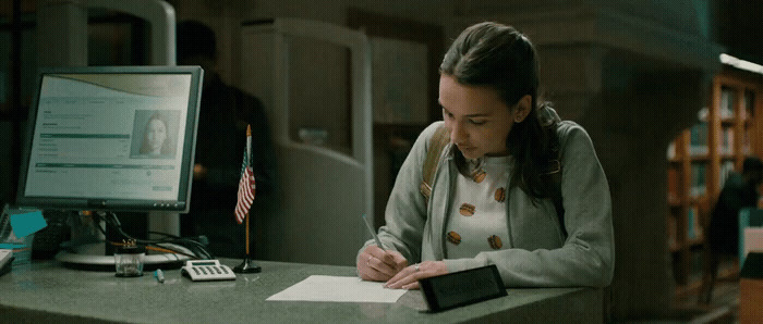 a woman sitting at a desk writing on a piece of paper