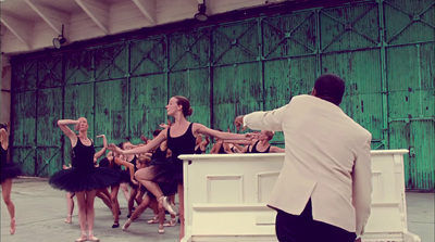 a man in a tuxedo standing in front of a group of dancers