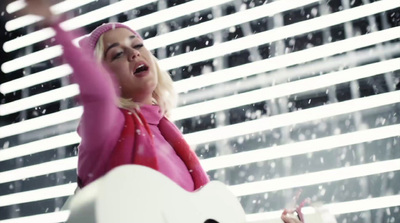 a woman in a pink jacket is holding a white guitar