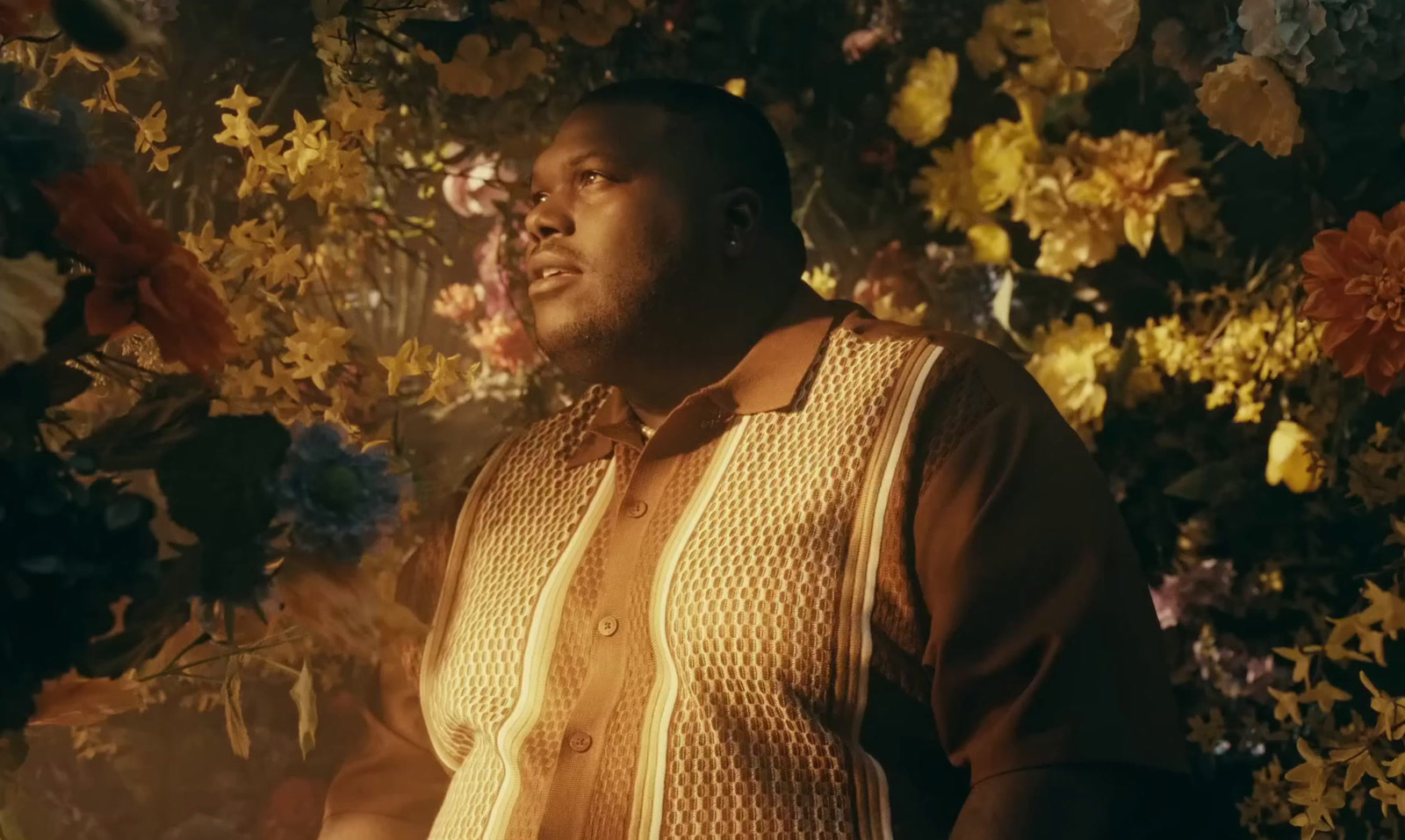 a man standing in front of a bunch of flowers