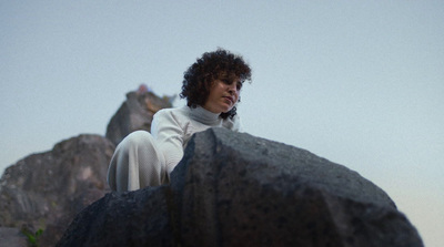 a woman sitting on top of a large rock