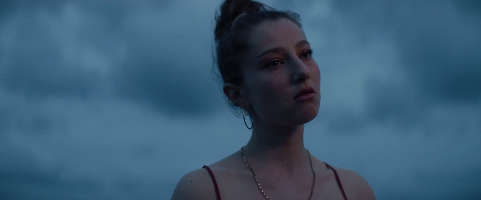 a woman in a red dress standing in front of a cloudy sky