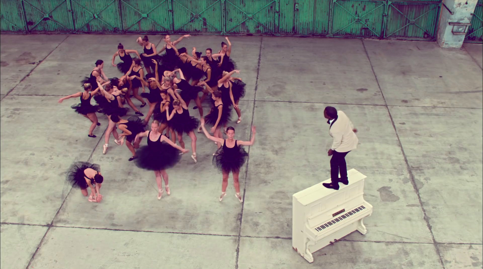 a man standing on top of a piano next to a group of dancers