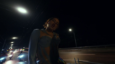 a woman standing on the side of a road at night