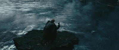 a man standing on a rock in the middle of a body of water