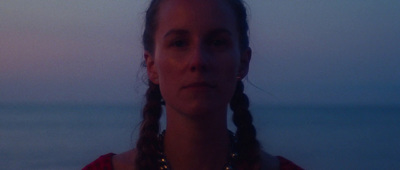 a woman with braids standing in front of a body of water