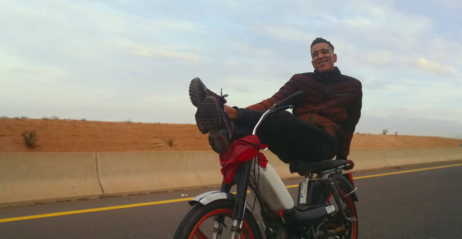 a man sitting on a motorcycle on the side of the road