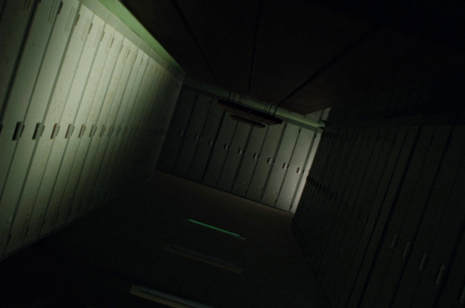 a dimly lit hallway with several lockers in it