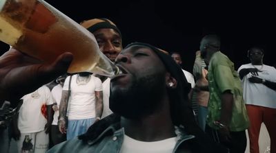 a man drinking a glass of beer in front of a group of men