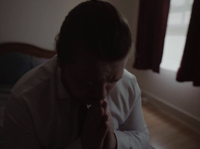 a man in a white shirt is praying