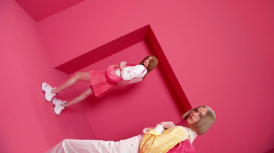 a man and a woman standing in front of a pink wall