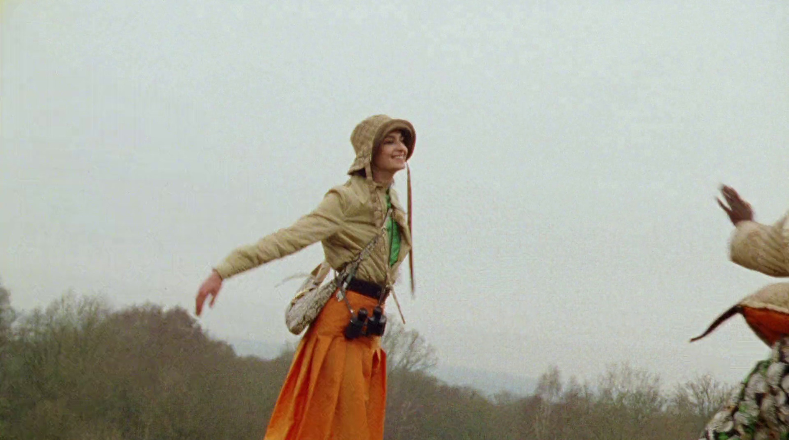 a woman in an orange dress is flying a kite