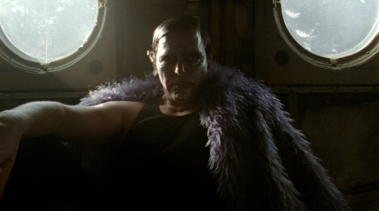 a man sitting in a chair with a fur stole around his neck