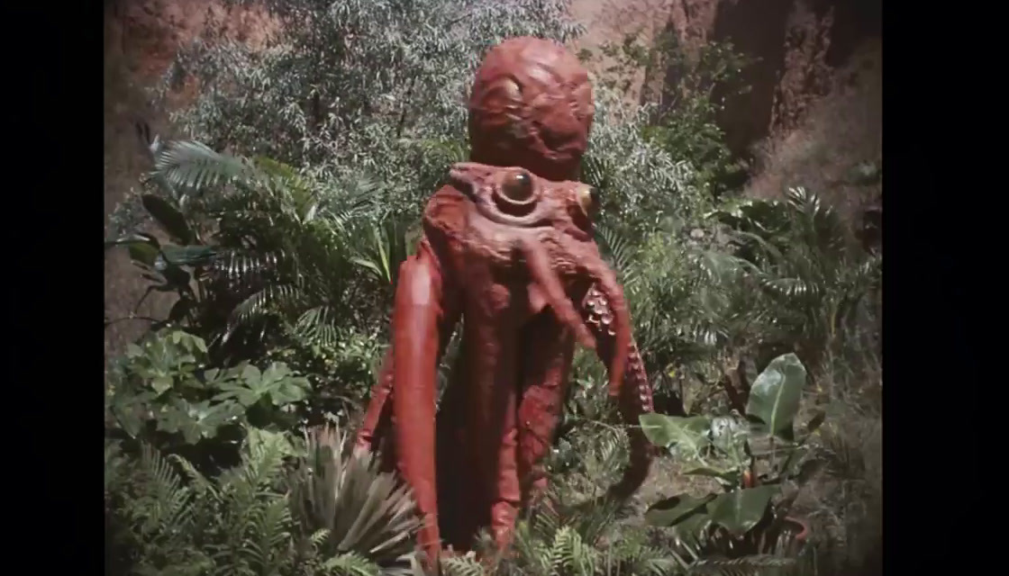 a red statue in the middle of a forest