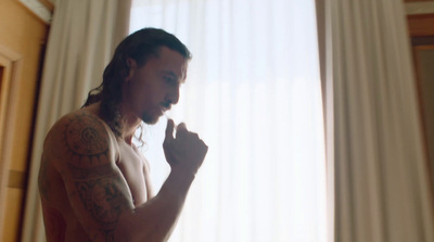 a man with tattoos standing in front of a window