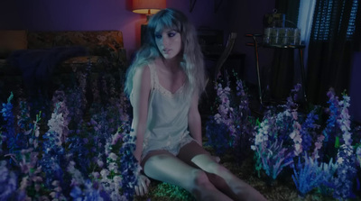 a woman sitting on a bed of purple flowers