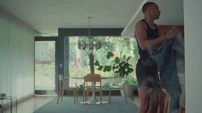 a man standing in a living room next to a dining room table